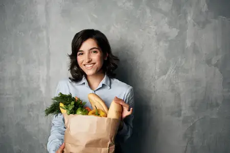Женщина с продуктовым пакетом, наполненным овощами, ведет здоровый образ жизни
