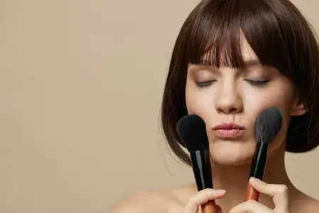 Портрет женщины с кистями для макияжа в руках