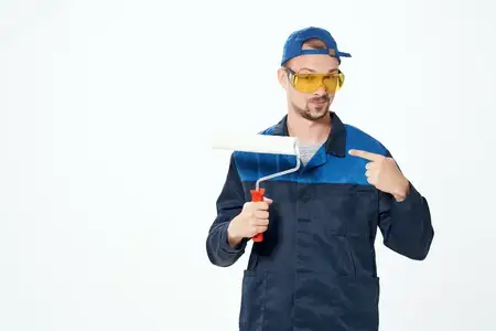Маляр-мужчина, профессиональный работник строительной сферы, выполняет свою работу
