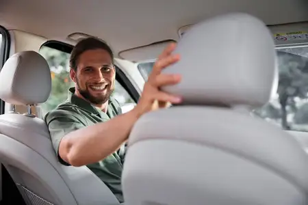 Улыбчивый бородатый мужчина наслаждается поездкой на автомобиле, сидя на заднем сиденье
