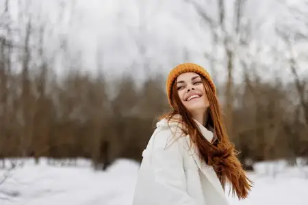 Счастливая молодая женщина с рыжими волосами гуляет на свежем зимнем воздухе