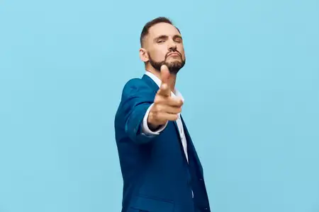 Он смотрит в камеру с твердым жестом и устойчивым взглядом, передавая динамику, лидерство, самообладание и сильную мотивацию в чистой студийной обстановке