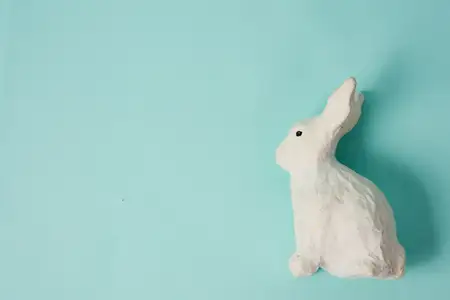 Праздничная игрушка — белый кролик на голубом фоне с пастельными цветами, Пасха