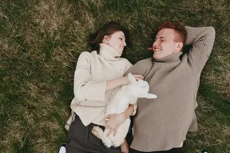 Молодая женщина и мужчина, одетые в уютные вязаные свитера, расслабляются на зеленой траве