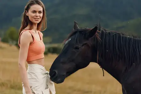 Спокойная сельская сцена: женщина и лошадь на зеленом лугу, создающие нежный, гармоничный момент дружбы и безмятежности на природе