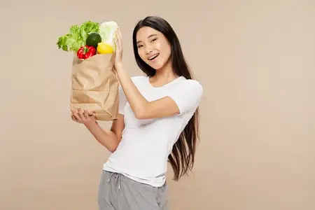 Женщина азиатской внешности с пакетом овощей, здоровая еда