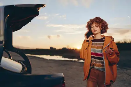 Женщина на отдыхе на улице рядом с машиной на закате на дороге