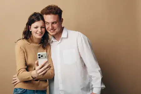 Счастливые молодые мужчина и женщина в повседневной одежде делают селфи на телефон