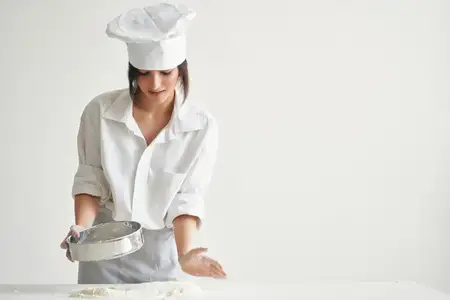 Женщина-пекарь работает с тестом на кухне, готовя выпечку