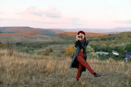 Женщина фотографирует природную красоту солнечного травянистого поля в спокойный день