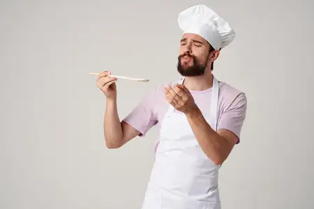 Повар-мужчина в фартуке профессионально идёт по кухне ресторана