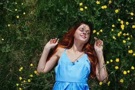 Весной женщина лежит на зелёной траве с жёлтыми цветами