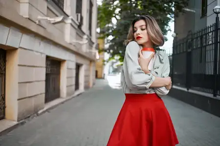 Веселая блондинка с чашкой кофе на улице ведет активный образ жизни