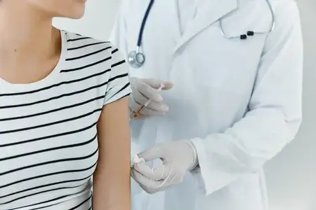 Врач в медицинских перчатках делает инъекцию вакцины в руку пациента, крупный план