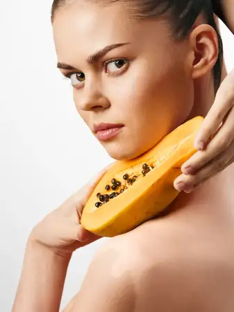 Женщина наносит мякоть папайи на шею
