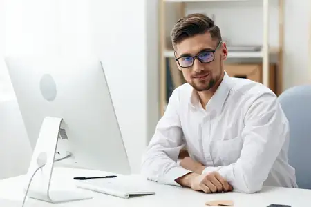 Бизнесмен в белой рубашке сидит за компьютером, работает в офисе