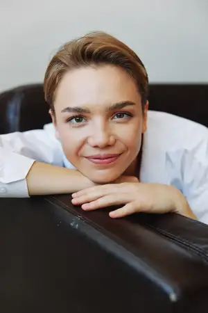 Портрет женщины с короткой стрижкой в белой рубашке, лежащей дома на диване