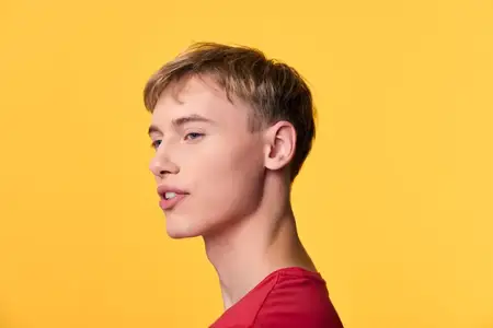 Профиль молодого человека в красной футболке на ярком жёлтом фоне, подчёркивающий современный студийный стиль, чистую композицию и универсальность для брендинга в рекламе и редакционных проектах
