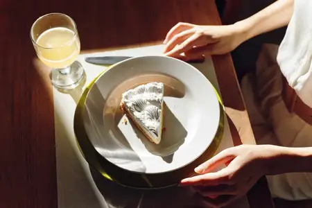 Элегантная женщина наслаждается романтическим ужином дома, смакуя вкусную домашнюю еду с блаженной улыбкой