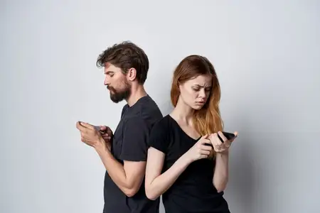 Мужчина и женщина с телефоном в руке, на их лицах читаются эмоции, на светлом фоне