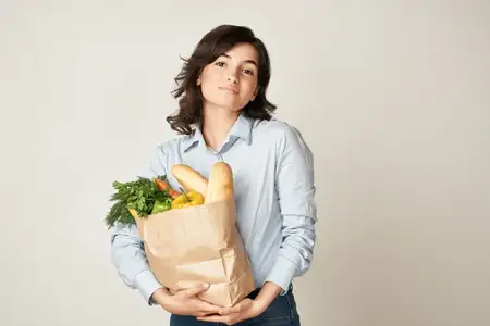Женщина с пакетом продуктов, домохозяйка, совершающая покупки в супермаркете