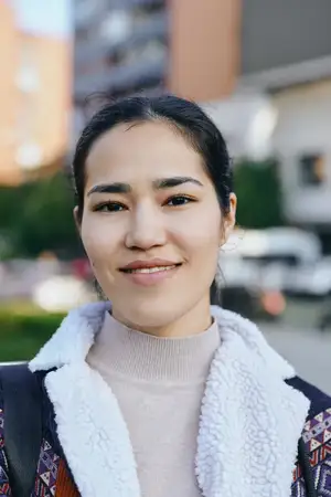 Уличный портрет улыбающейся женщины в повседневной одежде на солнечной улице