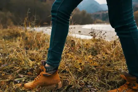 Женские ноги в ботинках и джинсах на природе осенью в горах