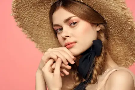 Портрет девушки в соломенной шляпе на розовом фоне