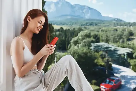 Симпатичная женщина с красным телефоном на террасе