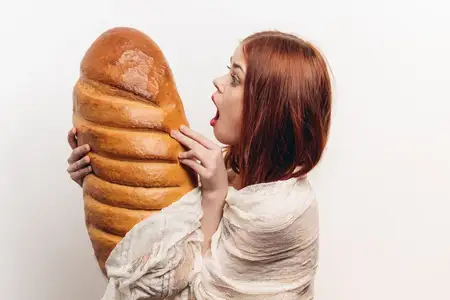 Буханка хлеба, мучные изделия, молодая женщина на светлом фоне, эмоции