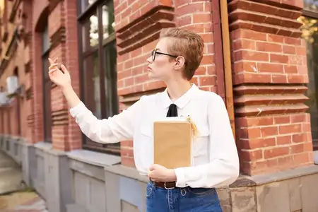 Короткостриженая женщина на улице возле здания отдыхает