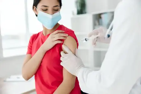 Врач держит шприц, делая инъекцию в плечо пациентке