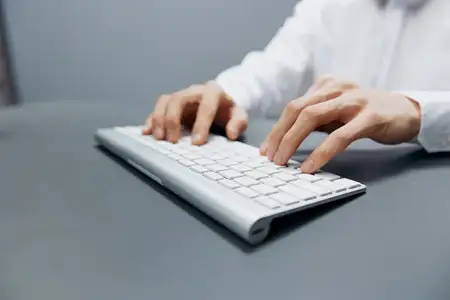 Работник сидит за столом с клавиатурой в офисе