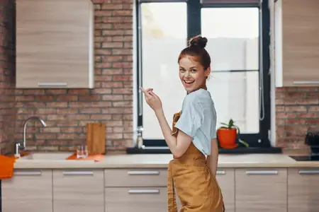 Симпатичная женщина в коричневом фартуке на кухне