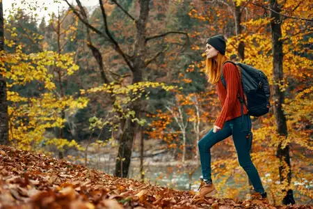 Женщина в осеннем лесу у реки, пейзаж с жёлтыми листьями, туризм
