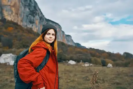 Женщина путешествует в горах с рюкзаком за спиной