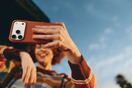 Женщина на улице держит смартфон для селфи