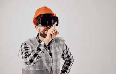 Строитель в оранжевой каске и 3D-очках жестикулирует руками на светлом фоне, свободное пространство