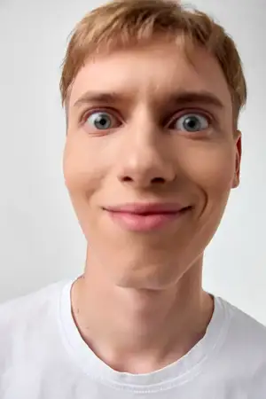 Выразительный крупный план с удивленными глазами и дружелюбной улыбкой, чистый фон, простая одежда, увлекательное настроение, непринужденное ощущение