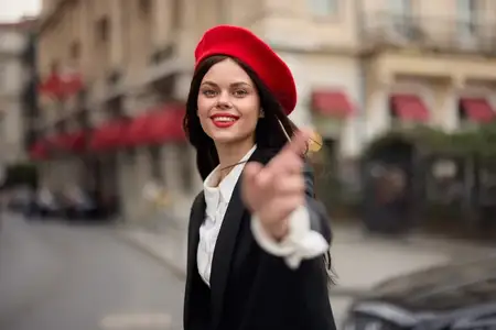 Модная женщина улыбается, стоя на улице на фоне города