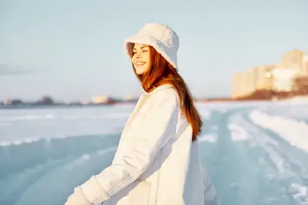 Молодая женщина в белом пальто и шапке на зимнем пейзаже, прогулка, путешествие