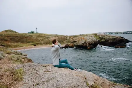 Симпатичная женщина в свитерах на фоне облачного моря, восхищается природой, без изменений