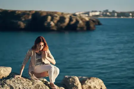 Женщина летом на пляже у моря в горах на фоне природного пейзажа