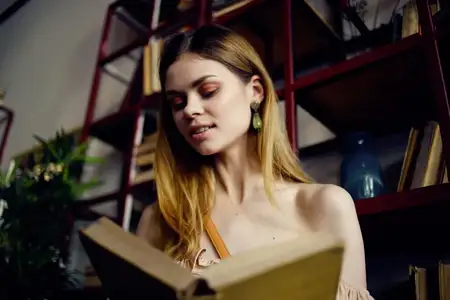 Красивая женщина с книгой в руках отдыхает в кафе