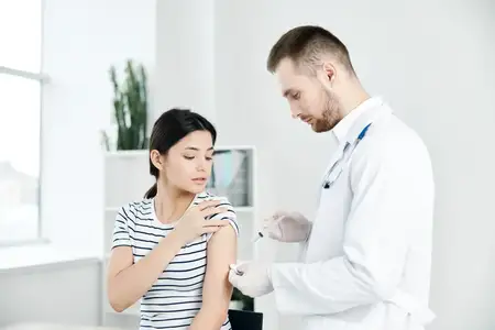 Доктор мужчина в белом халате делает инъекцию в плечо женщине-пациентке