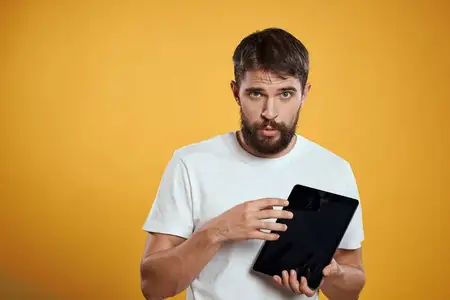 Мужчина с планшетом на желтом фоне, в белой футболке, новые технологии, бизнесмен, сенсорный экран, тачпад