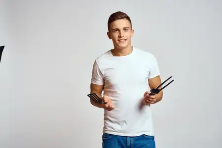 Парень с кухонными инструментами в руках на светлом фоне, кадрированное изображение, эмоции, веселье, модель