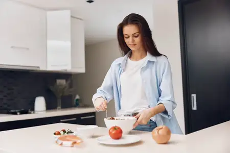 Молодая женщина готовит здоровую пищу дома на кухне, пропагандируя здоровое питание и образ жизни