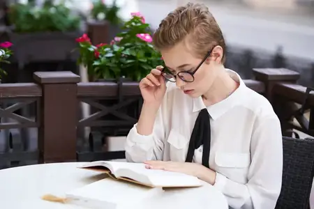Женщина в рубашке и галстуке за столом с книгой