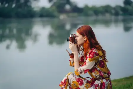 Женщина в разноцветном платье с фотоаппаратом в руках на улице
